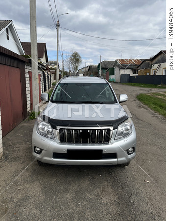 Silver SUV parked on rural street in small village neighborhood Silver SUV parked on rural street in small village neighborhood 139484065