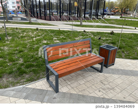 Modern wooden park bench with trash bin in residential courtyard Modern wooden park bench with trash bin in residential courtyard 139484069