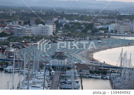 Seaport of Italian city of Rimini. Wide sandy sea beach resort with sun loungers and umbrellas on coast top view. Hotels apartments at night Seaport of Italian city of Rimini. Wide sandy sea beach resort with sun loungers and umbrellas on coast top view. Hotels apartments at night 139484092