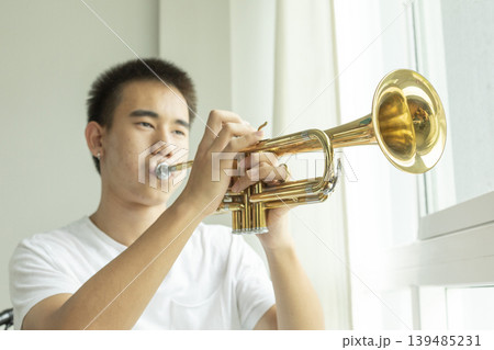 Teenage boy Learning To Play Trumpet In home school. Teenage boy Learning To Play Trumpet In home school. 139485231