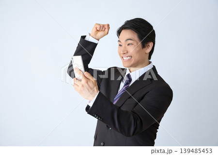 スマホを見てガッツポーズする会社員 139485453