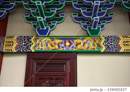 Colorful asian temple beam with golden dragons above red door 139485837