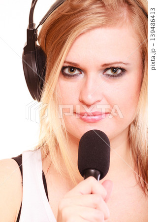 Woman singing to microphone wearing headphones Woman singing to microphone wearing headphones 139486413
