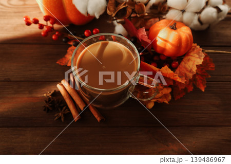 A warm drink rests in a clear mug surrounded by autumn leaves A warm drink rests in a clear mug surrounded by autumn leaves 139486967