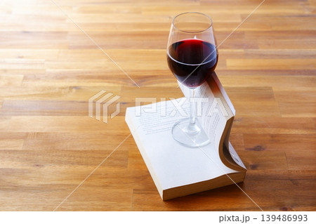 ワインのグラスと本 - 赤ワインを飲みながら読書を楽しんでいるイメージ 139486993