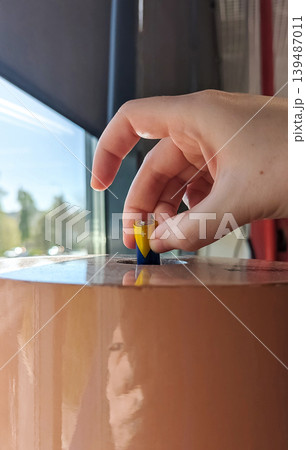 Close-up of a hand putting used batteries into a recycling bin in a supermarket. Concept of eco-friendly waste disposal and environment protection in a mall 139487011