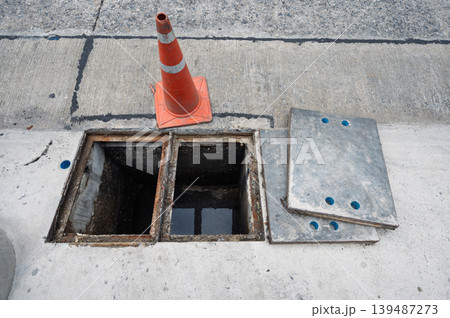 Dangerous open concrete drain hazard with warning traffic cone Dangerous open concrete drain hazard with warning traffic cone 139487273