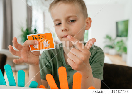 Young boy learning basic math by counting on his fingers at home. The scene highlights early childhood education and cognitive development in a comfortable 139487728