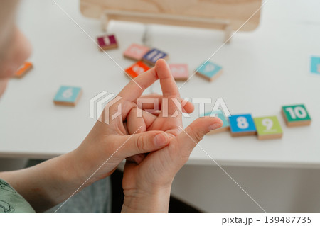 Close-up of a child counting numbers using fingers. Simple and intuitive learning method supporting early math development and number recognition. Close-up of a child counting numbers using fingers. Simple and intuitive learning method supporting early math development and number recognition. 139487735