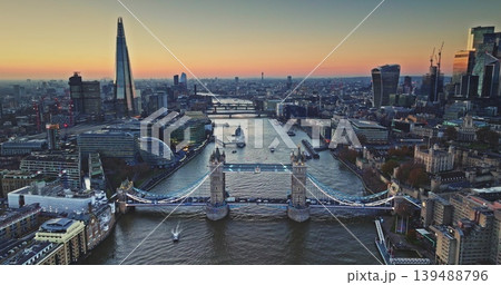 Evening London city landscape with iconic Tower Bridge standing over River Thames during a beautiful sunset, The Shard and other modern skyscrapers in cityscape background. Aerial view drone panorama Evening London city landscape with iconic Tower Bridge standing over River Thames during a beautiful sunset, The Shard and other modern skyscrapers in cityscape background. Aerial view drone panorama 139488796