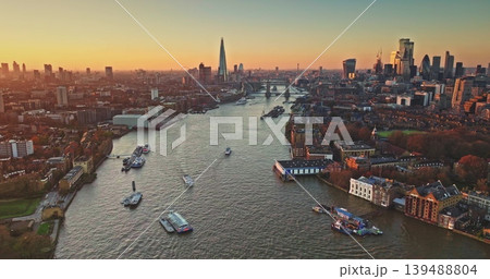 London cityscape panoramic aerial view, modern skyline at sunset, The Shard and Tower Bridge, boats navigate River Thames under bright colorful evening sky. England travel destination and landmarks London cityscape panoramic aerial view, modern skyline at sunset, The Shard and Tower Bridge, boats navigate River Thames under bright colorful evening sky. England travel destination and landmarks 139488804