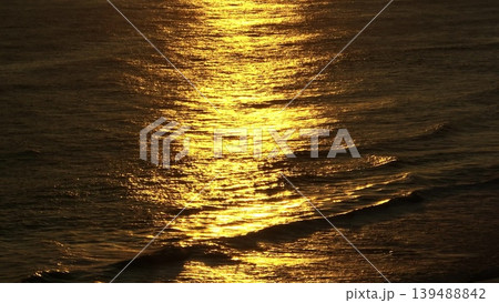 Golden sunlight gently reflecting on surface of dark ocean water and small waves, creating a shimmering, texture pattern during sunset at Bukit Peninsula, Bali. Natural background rise up panorama 139488842