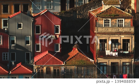 Porto houses vibrant facades and roofs, with laundry drying on lines, creating a lived-in urban scene under the afternoon sunlight. Aerial panorama shot of Portugal city. Architecture background Porto houses vibrant facades and roofs, with laundry drying on lines, creating a lived-in urban scene under the afternoon sunlight. Aerial panorama shot of Portugal city. Architecture background 139488859