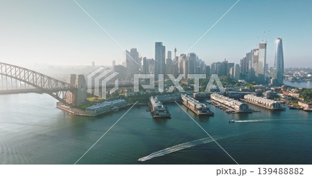 Australia, Sydney: Breathtaking aerial view of Sydney Harbour at sunrise, highlighting the Sydney Harbour Bridge, modern city skyline, and bustling boats navigating the water. Drone flight Australia, Sydney: Breathtaking aerial view of Sydney Harbour at sunrise, highlighting the Sydney Harbour Bridge, modern city skyline, and bustling boats navigating the water. Drone flight 139488882