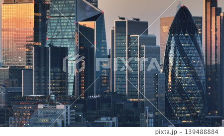 United Kingdom, London: Aerial view of London skyline at sunset, modern glass skyscrapers and the distinctive shape of 30 St Mary Axe, commonly known as The Gherkin, amidst the bustling cityscape United Kingdom, London: Aerial view of London skyline at sunset, modern glass skyscrapers and the distinctive shape of 30 St Mary Axe, commonly known as The Gherkin, amidst the bustling cityscape 139488884