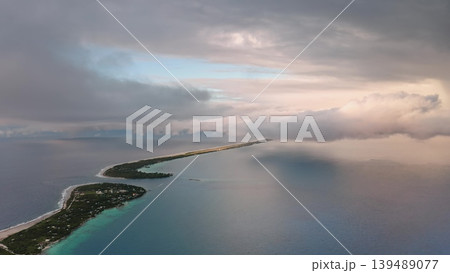 Breathtaking aerial view of Rangiroa Atoll partially covered by clouds during colorful sunset, showcasing the turquoise lagoon, lush vegetation, and surrounding ocean in French Polynesia. Drone flight Breathtaking aerial view of Rangiroa Atoll partially covered by clouds during colorful sunset, showcasing the turquoise lagoon, lush vegetation, and surrounding ocean in French Polynesia. Drone flight 139489077