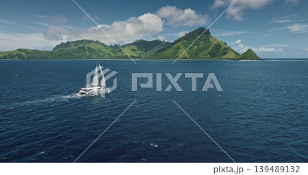 Fiji, Kuata island: Luxury catamaran sailing deep ocean water near green mountains tropical island, breathtaking aerial view. Remote wild nature paradise, exotic travel. Drone flight panorama Fiji, Kuata island: Luxury catamaran sailing deep ocean water near green mountains tropical island, breathtaking aerial view. Remote wild nature paradise, exotic travel. Drone flight panorama 139489132