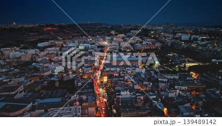 Malta, Comino island: Cars driving on illuminated urban traffic night road, showcasing vibrant cityscape streets lights and buildings with traditional and modern architecture. Drone flight Malta, Comino island: Cars driving on illuminated urban traffic night road, showcasing vibrant cityscape streets lights and buildings with traditional and modern architecture. Drone flight 139489142