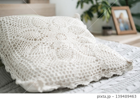 Elegant ivory crochet pillow on knitted bedspread in bright modern bedroom Elegant ivory crochet pillow on knitted bedspread in bright modern bedroom 139489463