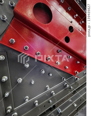 Industrial equipment with red and black metal components showing bolts and fittings in a workshop setting 139489827