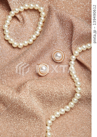 Beautiful pearl bracelet, earring, and necklace on beige texture background. Vertical photo 139490612