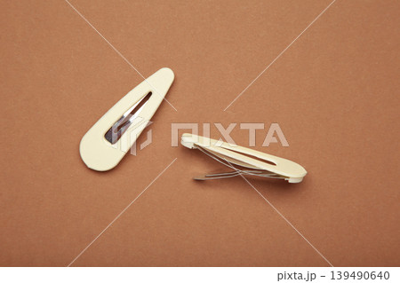 Beige hair clips on brown background. 139490640