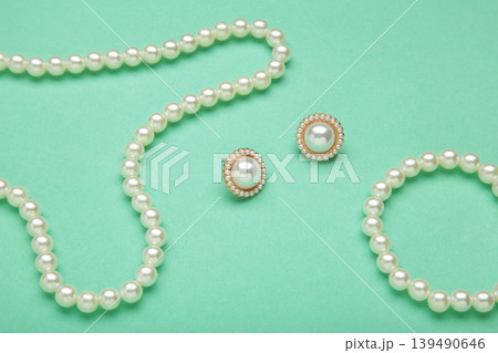 Beautiful pearl bracelet, earring, and necklace on mint background Beautiful pearl bracelet, earring, and necklace on mint background 139490646