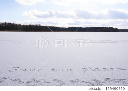 Written SAVE THE PLANET on snow background message ice outdoor on ground in winter. Writing text sign drawing on field in frozen background. Weather changing cold season has arrived environment 139490850