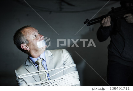 Scared man, kidnap and hands with gun for crime, ransom and negotiation, interrogation or abduction risk at night. Criminal, senior person or corporate hostage with duct tape, and tied up in basement Scared man, kidnap and hands with gun for crime, ransom and negotiation, interrogation or abduction risk at night. Criminal, senior person or corporate hostage with duct tape, and tied up in basement 139491711
