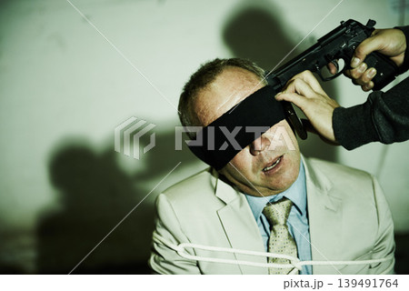Man, business and gun or kidnapped with rope or blindfolded, phone call for ransom hostage. Male person, criminal and fear weapon on chair for gangster interrogation, robber victim or mafia abduction Man, business and gun or kidnapped with rope or blindfolded, phone call for ransom hostage. Male person, criminal and fear weapon on chair for gangster interrogation, robber victim or mafia abduction 139491764