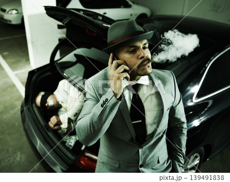 Phone call, car and man with abduction in trunk for negotiation, kidnapping ransom and crime. Mafia, gangster criminal and person smoking in boot for terrorism, danger and robbery in parking lot 139491838