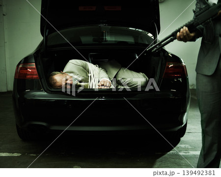 Man in trunk of car, kidnapping and gun with mafia, danger and violence in basement garage. Crime, human trafficking and scared person tied with rope parking lot with gangster, robbery and terror. Man in trunk of car, kidnapping and gun with mafia, danger and violence in basement garage. Crime, human trafficking and scared person tied with rope parking lot with gangster, robbery and terror. 139492381