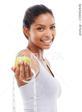 Happy woman, portrait and lose weight with a measuring tape and apple in white background or studio. Indian, model and healthy food for results in fitness, wellness and diet with nutrition and fruit Happy woman, portrait and lose weight with a measuring tape and apple in white background or studio. Indian, model and healthy food for results in fitness, wellness and diet with nutrition and fruit 139492646