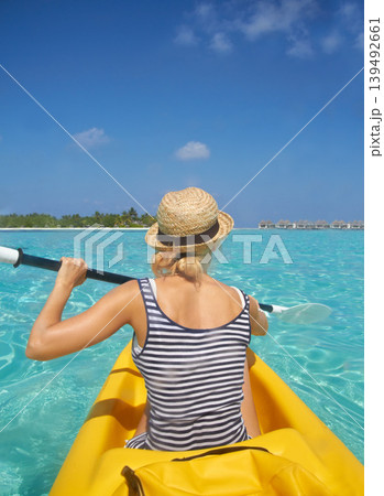 Woman, kayak and tropical ocean in summer in hat, mockup space or blue sky background by island. Person, boat or back for transport, holiday or travel on vacation in sunshine, water or sea for rowing 139492661