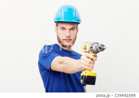 Construction worker man, power drill and studio portrait with hand for maintenance by white background. Person, employee or small business owner with tools, helmet and job at repair services company 139492899