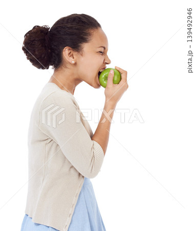 Woman, eating apple and healthy food choice for detox, dental health and wellness on a white background. Profile of a young person biting a green fruit for nutrition, strong teeth or vegan in studio 139492946