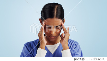 Doctor, studio or woman with headache, emergency or fatigue in medical healthcare crisis or head pain. Depression, face or tired nurse with burnout, migraine or stress isolated on blue background Doctor, studio or woman with headache, emergency or fatigue in medical healthcare crisis or head pain. Depression, face or tired nurse with burnout, migraine or stress isolated on blue background 139493204