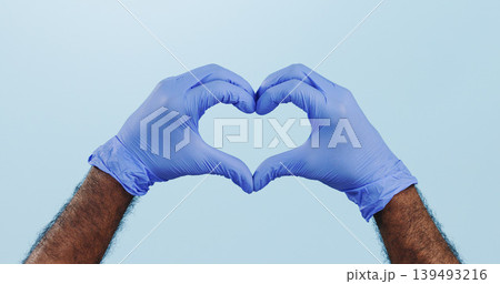 Man, doctor and heart hands with gloves for healthcare isolated against a blue studio background. Closeup of male person or medical nurse with like emoji, yes sign or shape for love or care on mockup Man, doctor and heart hands with gloves for healthcare isolated against a blue studio background. Closeup of male person or medical nurse with like emoji, yes sign or shape for love or care on mockup 139493216
