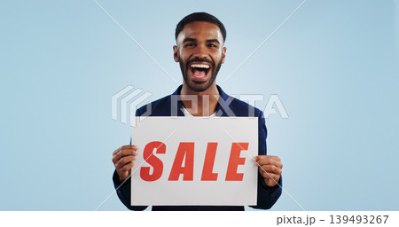 Excited man, portrait and sale sign for advertising, deal or discount against a blue studio background. Happy male person showing billboard or poster for marketing, promotion or special on mockup 139493267