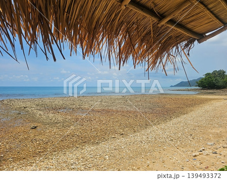 Scenic Tropical Beach View Framed by a Rustic Thatched Straw Roof 139493372
