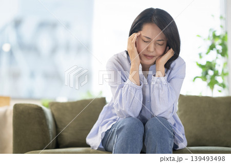 ソファに座り頭を抱える40代の女性 139493498