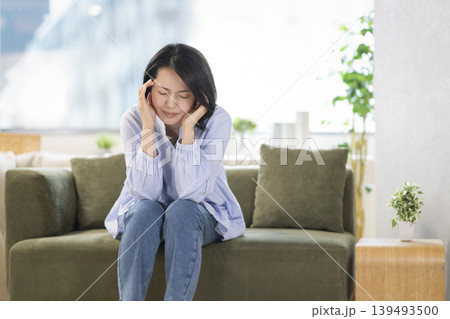 ソファに座り頭を抱える40代の女性 139493500