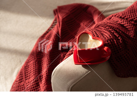 Heart Shaped Coffee Cup on Armchair with Red Blanket. Cozy Valentines Day Still Life Heart Shaped Coffee Cup on Armchair with Red Blanket. Cozy Valentines Day Still Life 139493781
