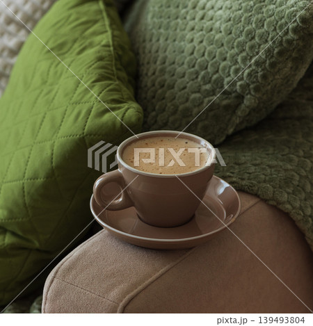 Cup of Hot Coffee Stay on Arm of Cozy Couch by Blanket 139493804