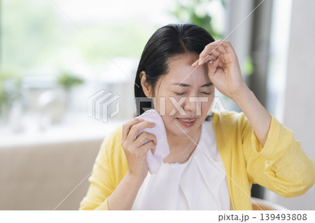 額の汗を拭く40代半ばの女性 額の汗を拭く40代半ばの女性 139493808
