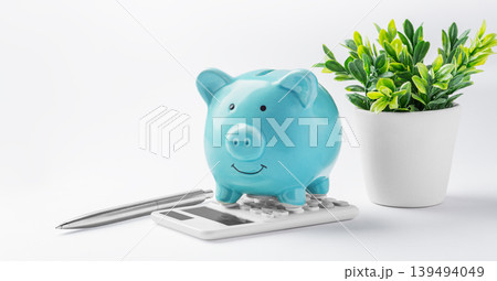 Piggy bank on calculator with pen and green plant on white background, saving and investment concept Piggy bank on calculator with pen and green plant on white background, saving and investment concept 139494049