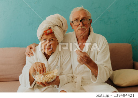 Happy senior couple watching TV and eating popcorn. Happy senior couple watching TV and eating popcorn. 139494421