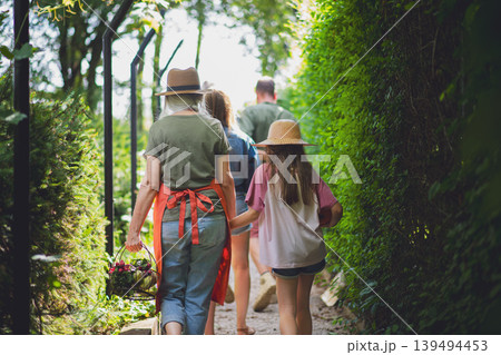 Rear view of farmers carrying basket with harvest and looking at homegrown vegetables outdoors at community garden. 139494453