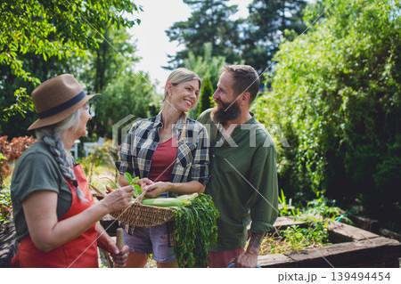 Farmers carrying basket with harvest and looking at homegrown vegetables outdoors at community garden. Farmers carrying basket with harvest and looking at homegrown vegetables outdoors at community garden. 139494454