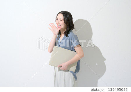 白背景でノートパソコンを持って呼びかける日本人女性 139495035